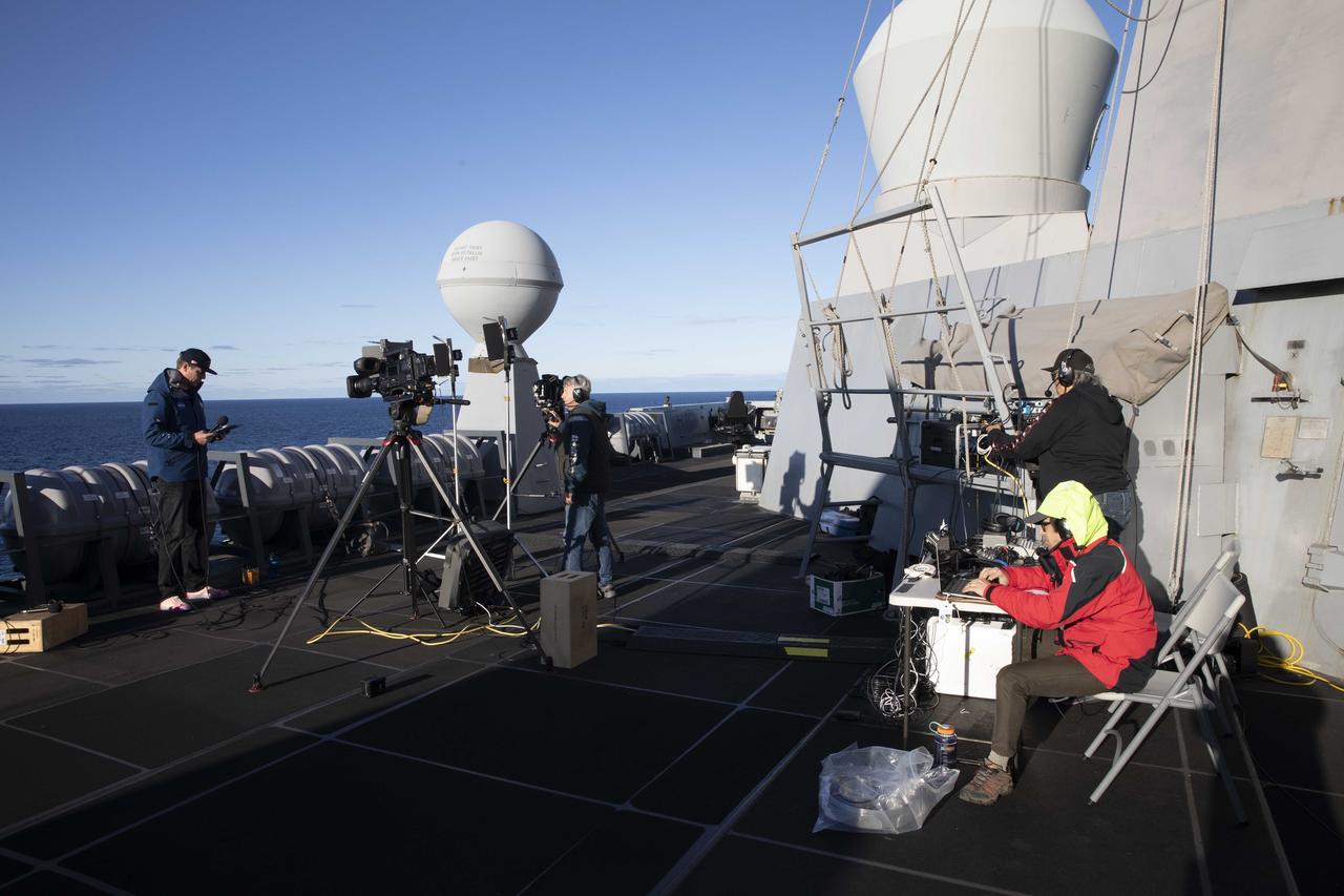 Members of Kennedy Space Center’s public affairs team prepare for live coverage of NASA’s Orion spacecraft’s splashdown for the Artemis I mission while aboard USS Portland. Orion safely splashed down in the Pacific Ocean on Dec. 11, 2022, completing a 25.5 day mission around the Moon and back.