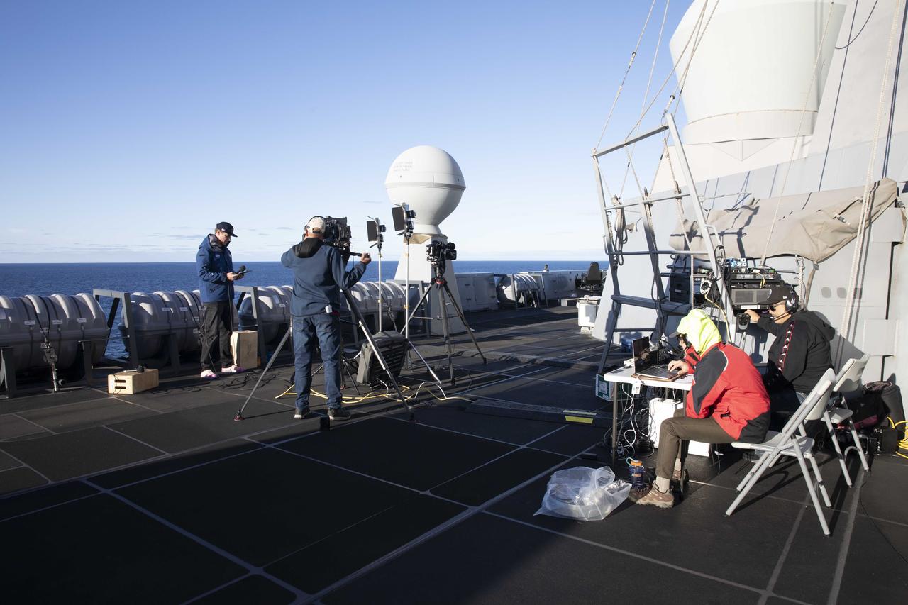 Members of Kennedy Space Center’s public affairs team prepare for live coverage of NASA’s Orion spacecraft’s splashdown for the Artemis I mission while aboard USS Portland. Orion safely splashed down in the Pacific Ocean on Dec. 11, 2022, completing a 25.5 day mission around the Moon and back.