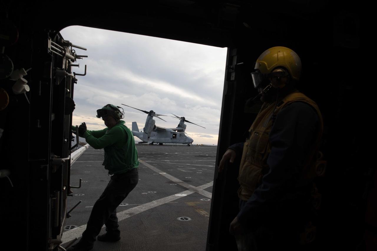 A member of the U.S. Navy helicopter team aboard USS Portland opens a door to the flight deck after a V-22 Osprey lands prior to NASA’s Orion splashdown for the Artemis I mission on Dec. 11, 2022.