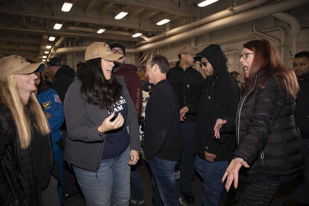NASA Artemis Launch Director Charlie Blackwell-Thompson, at right, and Melissa Jones, NASA’s Artemis I Recovery director, second from left, both with the Exploration Ground Systems program, along with other recovery team members, exchange congratulations inside the well deck of the USS Portland at U.S. Naval Base San Diego on Dec. 13, 2022. The Orion spacecraft is secured inside the well deck after splashing down at 12:40 p.m. EST on Dec. 11, 2022. U.S. Navy divers helped recover the Orion spacecraft. NASA, the Navy and other Department of Defense partners worked together to secure the spacecraft inside the ship’s well deck approximately five hours after Orion splashed down in the Pacific Ocean off the coast of Baja, California.