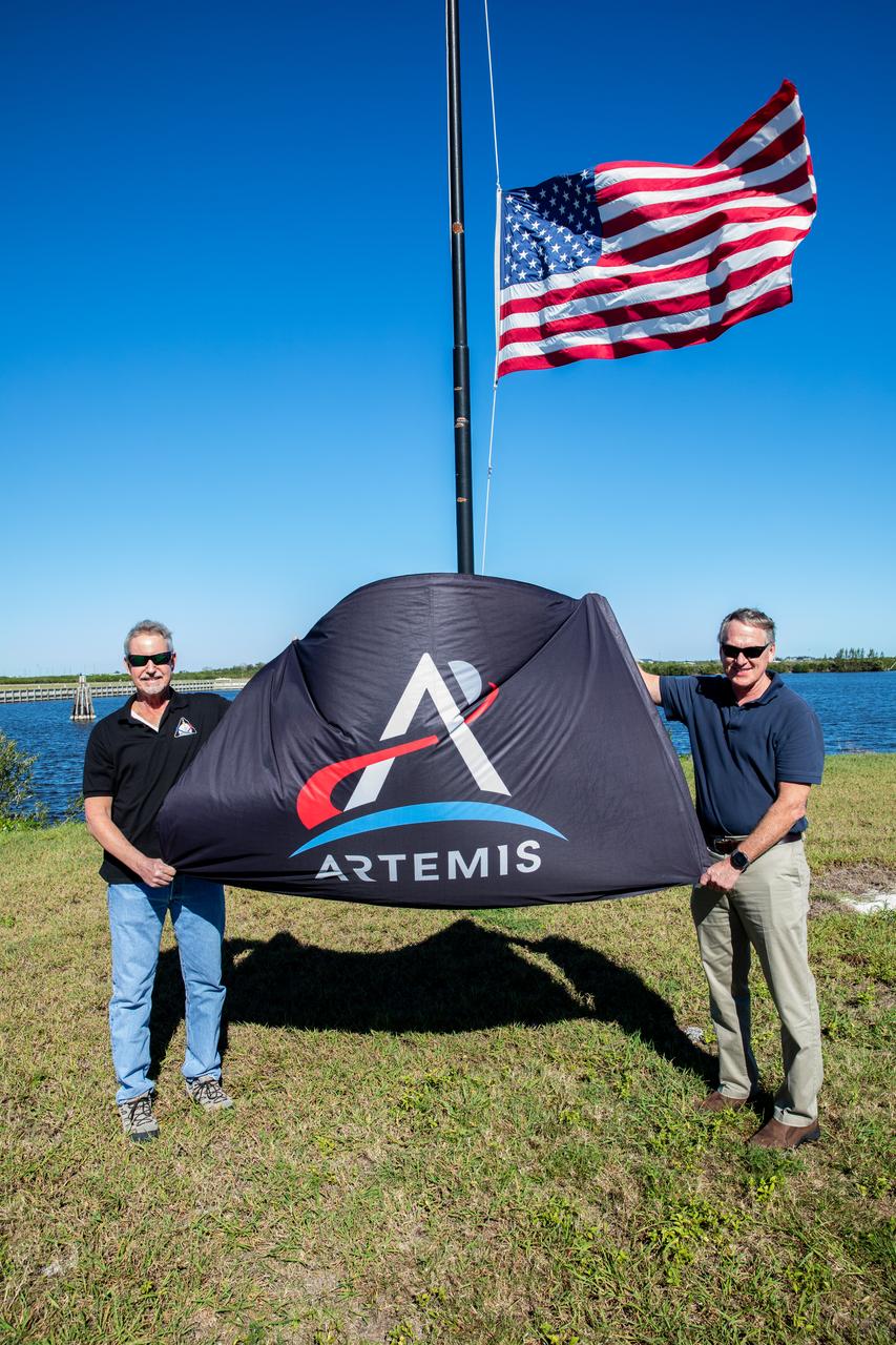 The Artemis flag is removed from NASA News Center property at the agency’s Kennedy Space Center in Florida on Jan. 6, 2023, following the successful Artemis I mission. At left is former Exploration Ground Systems (EGS) Senior Technical Integration Manager Phil Weber, joined by former EGS Manager Mike Bolger. Both men served in their respective roles during Artemis I, retiring at the end of 2022. NASA’s Space Launch System (SLS) rocket and Orion spacecraft lifted off from Kennedy’s Launch Complex 39B on Nov. 16, 2022. Orion splashed down in the Pacific Ocean on Dec. 11 and arrived back at Kennedy on Dec. 30. Artemis I sets the stage for the next mission of SLS and Orion to fly crew around the Moon on Artemis II.