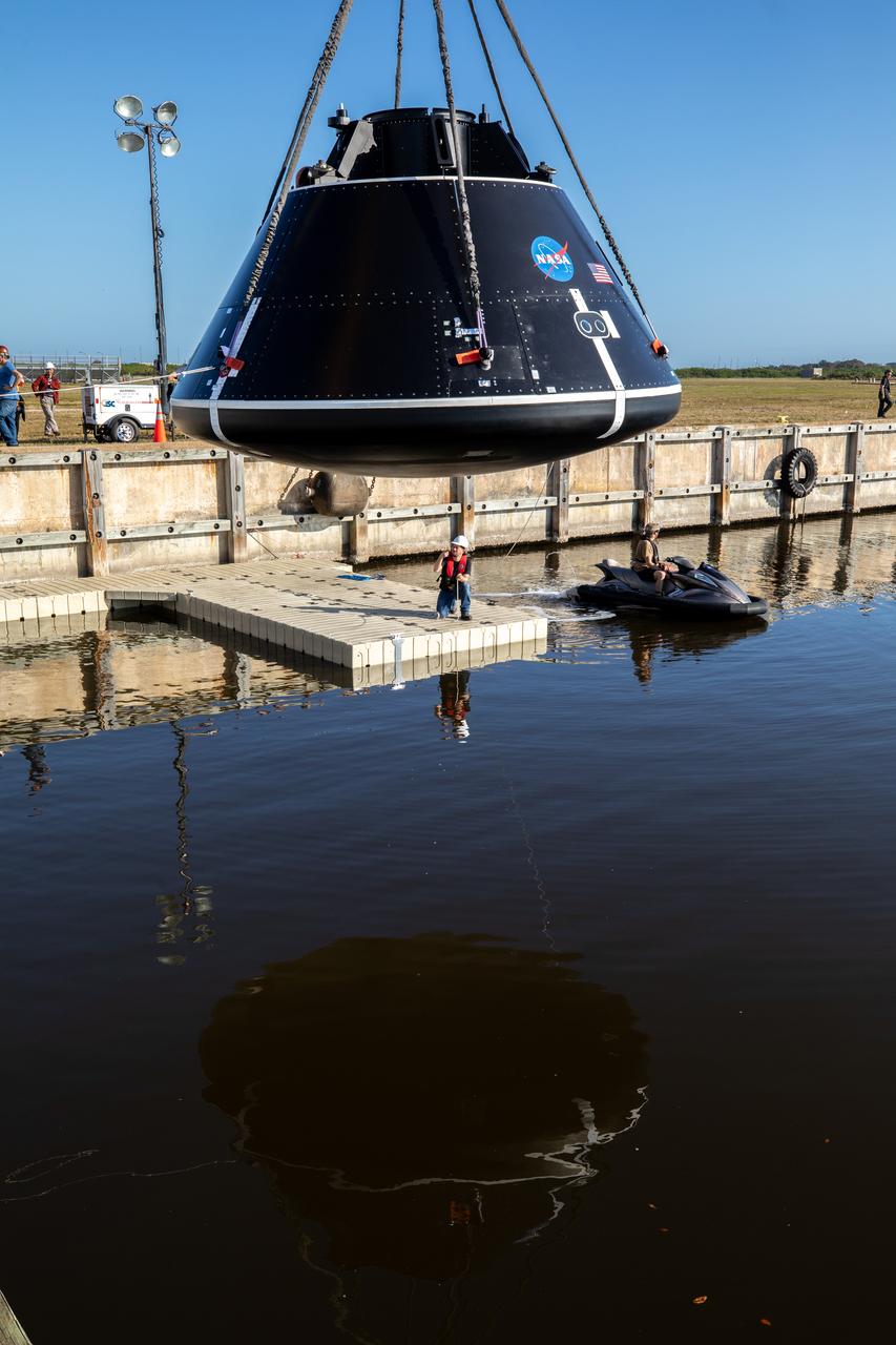 A crane is used to hold the Crew Module Test Article (CMTA) above the water at the turn basin in the Launch Complex 39 area at NASA’s Kennedy Space Center in Florida on Jan. 30, 2023. The CMTA is being used to practice recovery after splashdown of the Orion spacecraft to prepare for the Artemis II crewed mission. Exploration Ground Systems leads recovery efforts. 