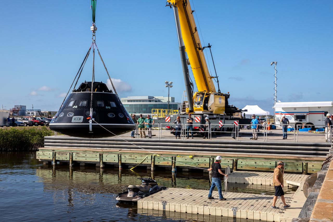 A crane is used to hold the Crew Module Test Article (CMTA) above the water at the turn basin in the Launch Complex 39 area at NASA’s Kennedy Space Center in Florida on Jan. 30, 2023. The CMTA is being used to practice recovery after splashdown of the Orion spacecraft to prepare for the Artemis II crewed mission. Exploration Ground Systems leads recovery efforts. 