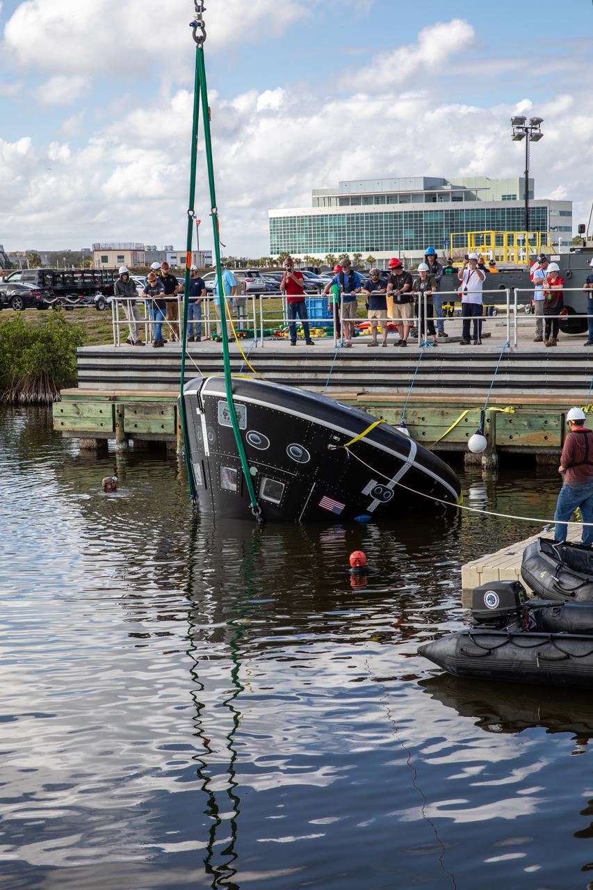 A crane is used to turn the Crew Module Test Article (CMTA) upside down in the water at the turn basin in the Launch Complex 39 area at NASA’s Kennedy Space Center in Florida on Jan. 31, 2023. The CMTA is being certified for use to practice recovery after splashdown of the Orion spacecraft to prepare for the Artemis II crewed mission. Exploration Ground Systems leads recovery efforts.
