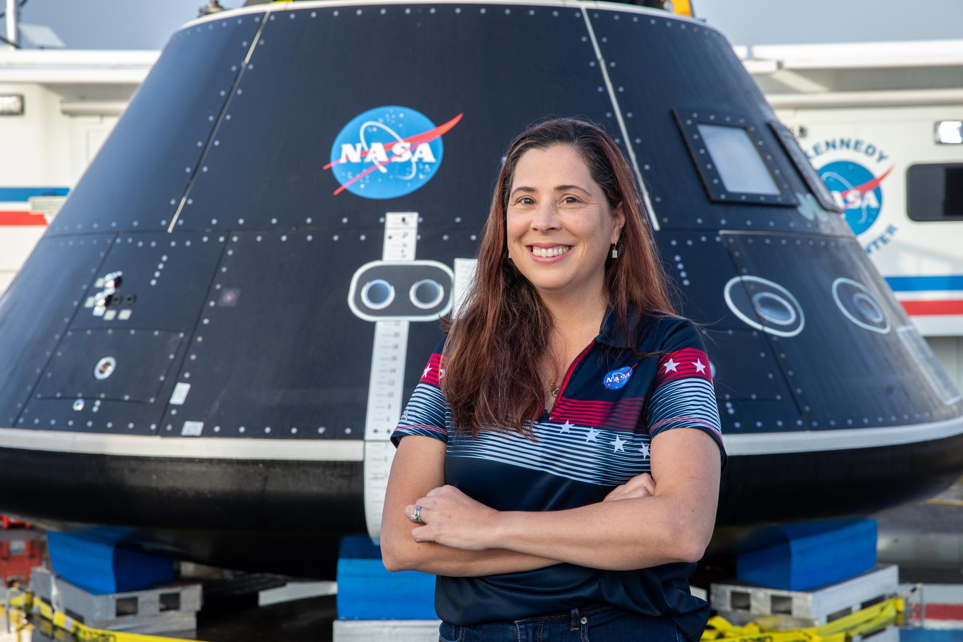 Liliana Villarreal, Artemis landing and recovery director with Exploration Ground Systems (EGS), stands in front of the Crew Module Test Article (CMTA) at the turn basin in the Launch Complex 39 area at NASA’s Kennedy Space Center in Florida on Feb. 1, 2023.