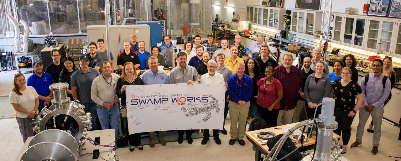 To celebrate its 10-year anniversary, the Swamp Works team poses for a group photograph inside the Swamp Works laboratory area at NASA’s Kennedy Space Center in Florida on April 21, 2023. Swamp Works includes several laboratories where hands-on, cutting-edge technology is developed for NASA and its exploration goals, as well as for benefits on Earth.