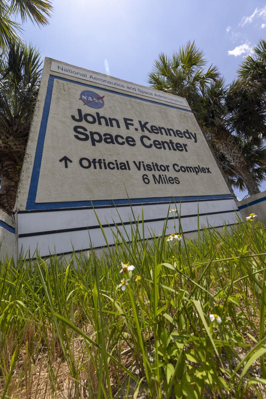 Wildflowers and palm trees are in view near a sign marking the entrance to NASA’s John F. Kennedy Space Center in Florida on May 19, 2023. The center shares a border with the Merritt Island National Wildlife Refuge. More than 330 native and migratory bird species, along with 65 amphibian and reptile species, call Kennedy and the wildlife refuge home. 
