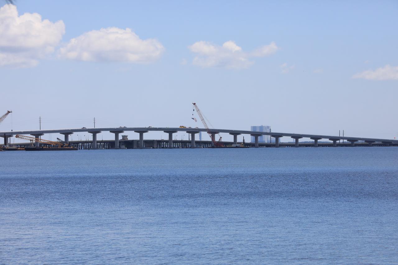 In view is the upgraded eastbound span of the Indian River Bridge leading to NASA’s Kennedy Space Center in Florida. A ribbon cutting ceremony was held June 9, 2023 to officially open the East part of the bridge. The new high-rise bridge serves as the primary entrance and exit to the space center for employees and visitors. The bridge spans the Indian River Lagoon and connects Kennedy and the Cape Canaveral Space Force Station to the mainland via State Road 405/NASA Causeway in Titusville. This first section of the bridge replaces the two-lane drawbridge which was built in the mid-1960s to support the Apollo program. 