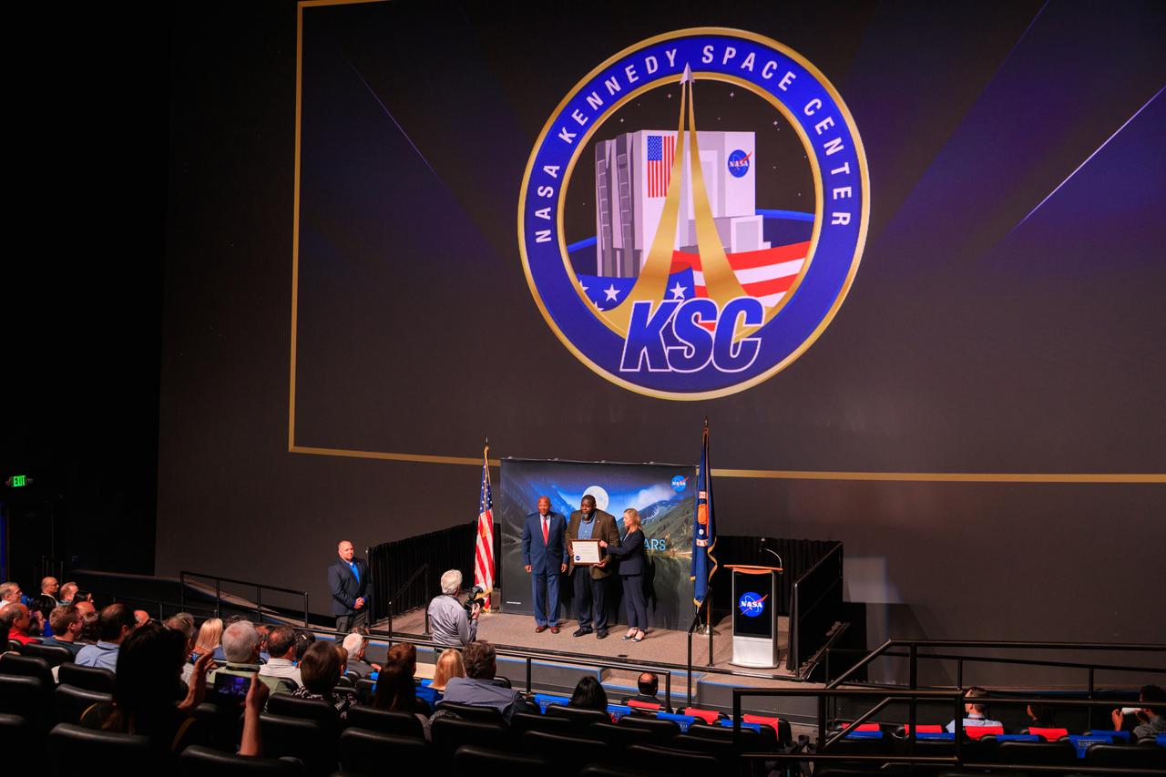 NASA’s Kennedy Space Center Director Janet Petro (right) and Deputy Director Kelvin Manning (left) present a KSC Certificate of Appreciation to Malcom Boston at the center's 2022 KSC Honor Awards Ceremony inside the IMAX Theater at the Florida spaceport’s nearby Visitor Complex on June 13, 2023. Kennedy Space Center employees, award recipients, families, and friends attended the ceremony, which honored both civil servants and contractors for their contributions to NASA and Kennedy.