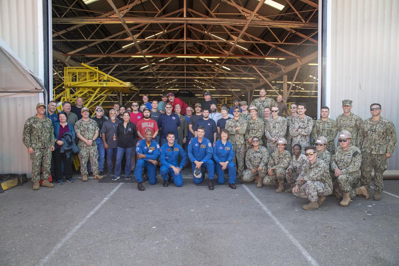 From left to right, NASA astronaut Victor Glover, Canadian Space Agency astronaut Jeremy Hansen, NASA astronauts Reid Wiseman and Christina Hammock Koch, pose with teams from NASA’s Exploration Ground Systems Program and sailors from the U.S. Navy assigned to Amphibious Construction Battalion 1 during a tour of Defense Distribution Depot Center in San Diego, California, on July 19, 2023. The depot is currently being used by NASA to house the Vehicle Advanced Demonstrator for Emergency Recovery, “VADER”, a replica of the space capsule. In preparation for NASA's Artemis II crewed mission, which will send four astronauts in Orion beyond the Moon, NASA and the U.S. Navy will conduct a series of tests to demonstrate and evaluate the processes, procedures, and hardware used in recovery operations for crewed lunar missions. The approximately 10-day flight of Artemis II will test NASA's foundational human deep space exploration capabilities, the Space Launch System rocket and Orion spacecraft, for the first time with astronauts and will pave the way to establishing a long-term presence at the Moon for science and exploration through Artemis. 