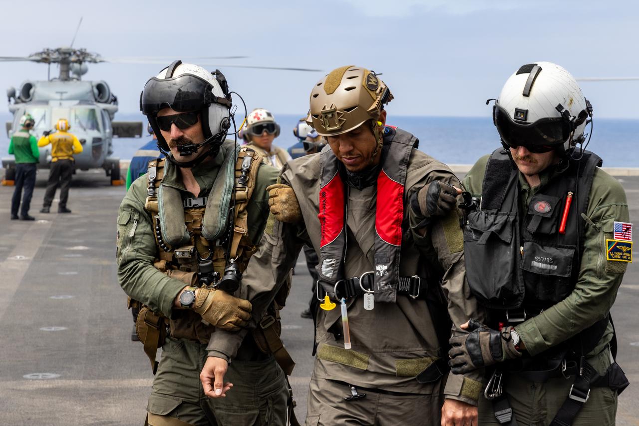 Naval helicopter pilots from Helicopter Sea Combat Squadron (HSC) 23 “Wildcards” escort a pilot acting as an Artemis II astronaut on the ships flight deck during an Artemis II mission recovery simulation as part of NASA’s Underway Recovery Test 10 off the coast of San Diego. HSC-23 will be responsible for flying the Artemis II crew from the Orion spacecraft to the recovery vessel once they splash down after a 10-day mission around the Moon.