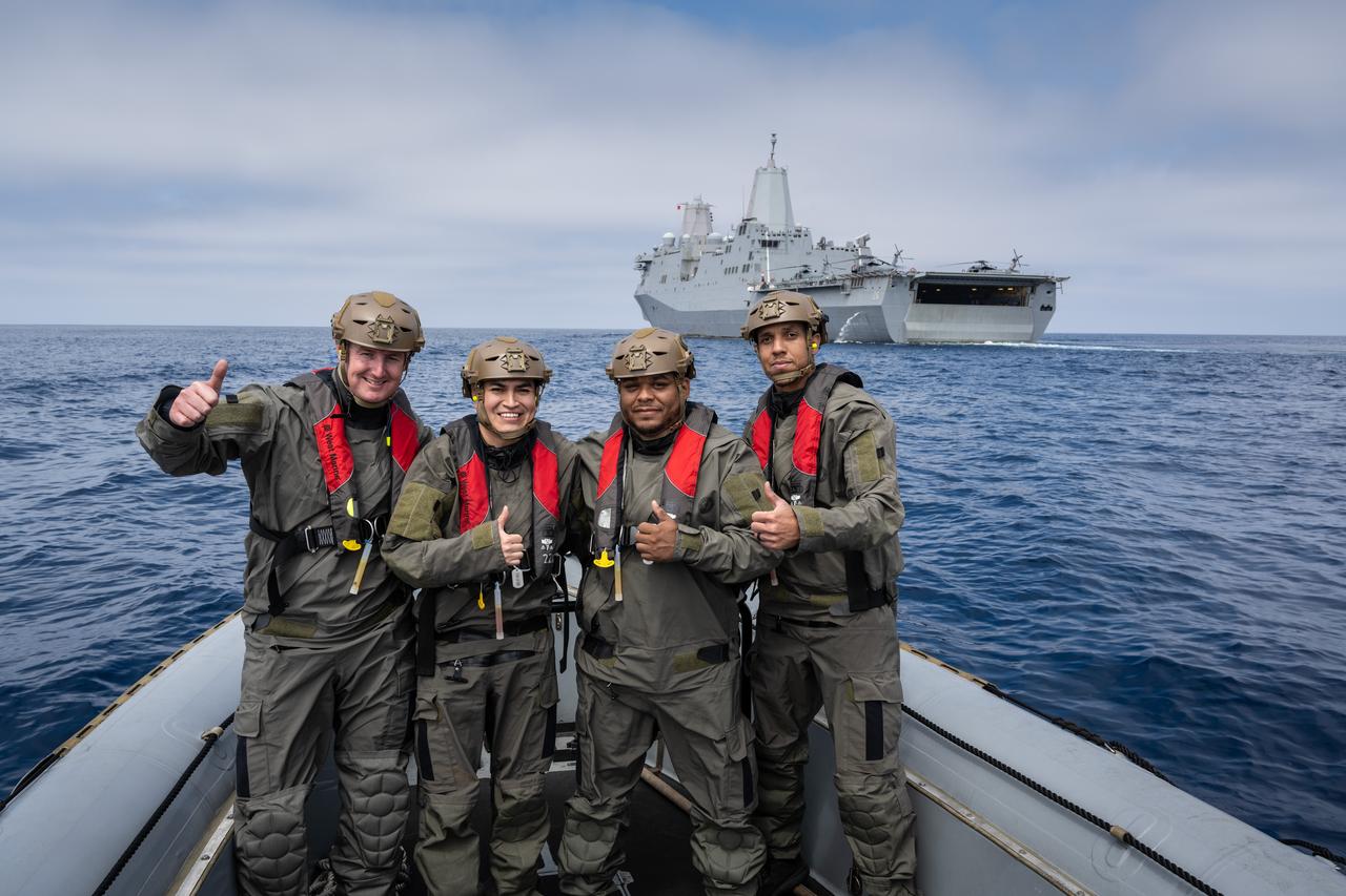 Four Naval helicopter pilots from Helicopter Sea Combat Squadron (HSC) 23 “Wildcards” pose for a photo in the Pacific Ocean as they prepare to participate in an Artemis II recovery test as part of NASA’s Underway Recovery Test 10. During recovery practice, these four pilots acted as Artemis II astronauts and were placed inside the Orion Crew Module Test Article, recovered from the capsule onto an inflatable “front porch” and then lifted via helicopter back to the flight deck of USS John P Murtha.