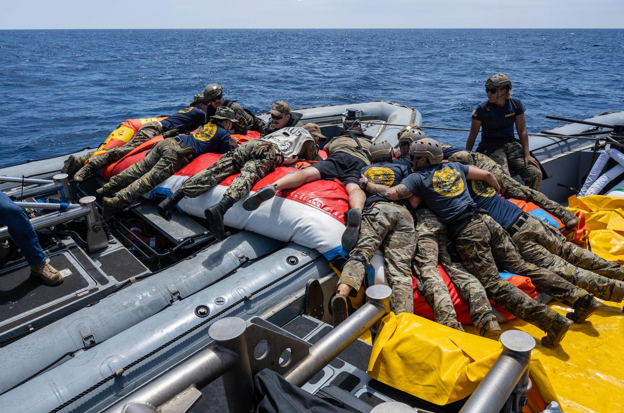 Navy Divers from Explosive Ordnance Disposal (EOD) Expeditionary Support Unit 1, sailors from USS John P Murtha and NASA Open Water Lead, Tim Goddard, work to deflate Artemis recovery equipment after a simulated Artemis recovery operation as part of NASA’s Underway Recovery Test 10. The team will use these inflatables as a platform for astronauts as they exit the Orion spacecraft after splashing down in the Pacific Ocean 