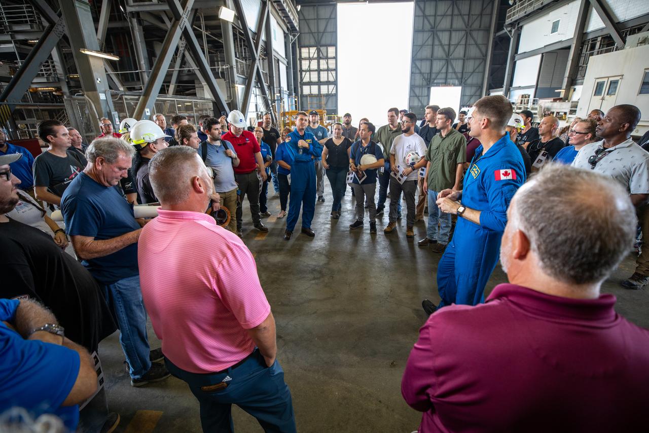 Artemis II NASA astronaut Reid Wiseman, in the center, and Jeremy Hansen, at right, CSA (Canadian Space Agency) Artemis II astronaut, talk with members of the Exploration Ground Systems team inside the transfer aisle of the Vehicle Assembly Building during a visit to the agency’s Kennedy Space Center in Florida on Aug. 7, 2023. The approximately 10-day Artemis II flight will test NASA’s foundational human deep space exploration capabilities, the Space Launch System rocket and Orion spacecraft, for the first time with astronauts and will pave the way for lunar surface missions, including landing the first woman and the first person of color on the Moon. 