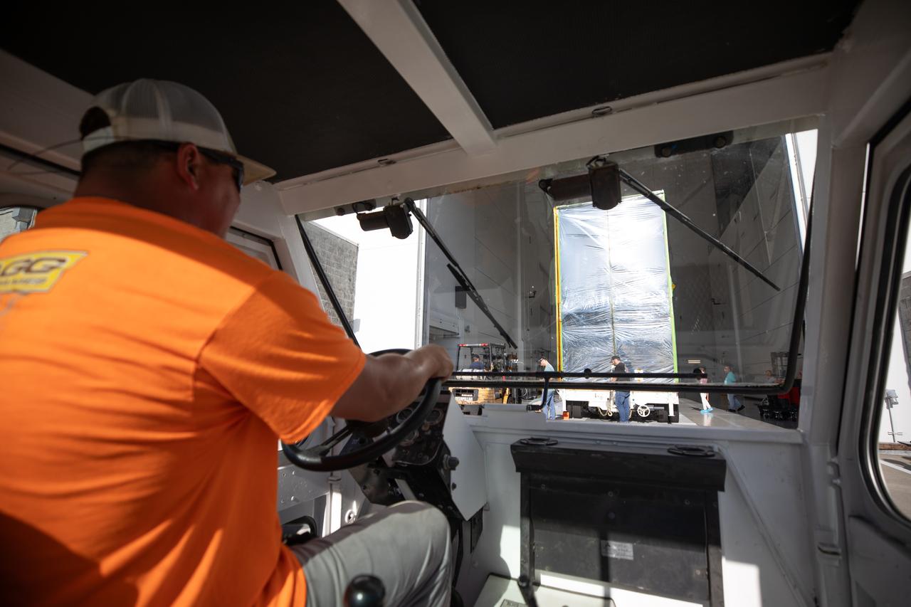 A driver uses a transport vehicle to move NASA’s Psyche spacecraft, secured for transport, into the entrance of Building 9 at the Astrotech Space Operations Facility near the agency’s Kennedy Space Center in Florida on Aug. 14, 2023.  Psyche will explore its namesake, a metal-rich asteroid orbiting the Sun between Mars and Jupiter. Psyche has NASA’s Deep Space Optical Communications (DSOC) technology demonstration onboard the spacecraft. DSOC will be the agency's first demonstration of optical communication beyond the Moon. Psyche will launch atop a SpaceX Falcon Heavy rocket from Launch Complex 39A at Kennedy. Launch is targeted for Oct. 5, 2023. 