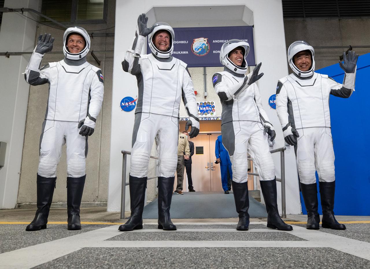 NASA’s SpaceX Crew-7 crew members, from left, Roscosmos cosmonaut Konstantin Borisov, ESA (European Space Agency) astronaut Andreas Mogensen, NASA astronaut Jasmin Moghbeli, and JAXA (Japan Aerospace Exploration Agency) astronaut Satoshi Furukawa acknowledge family and friends on Saturday, Aug. 26, 2023, outside of the Neil Armstrong Operations and Checkout Building at NASA’s Kennedy Space Center in Florida. Next, they will get into the customized Tesla Model X vehicles that will transport them to Kennedy’s Launch Complex 39A. SpaceX’s Dragon spacecraft, powered by the company’s Falcon 9 rocket, will carry the four-person crew to the International Space Station as part of NASA’s Commercial Crew Program. Crew-7 is scheduled to launch at 3:27 a.m. EDT.