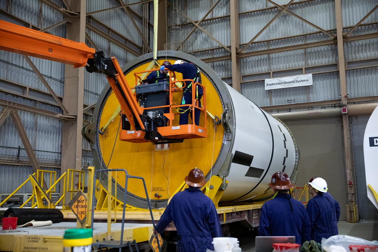 Engineers and technicians process the right forward center segment of the Space Launch System solid rocket boosters for the Artemis II mission inside the Rotation, Processing and Surge Facility (RPSF) at NASA’s Kennedy Space Center in Florida by removing the yellow cap and inspecting propellant on Monday, Nov. 27, 2023. Since arriving via rail in September, the team has been examining each segment one-by-one to make sure they are ready for integration and launch before being moved to the Vehicle Assembly Building for stacking atop the mobile launcher. Artemis II astronauts Reid Wiseman, Victor Glover, Christina Koch, and Jeremy Hansen will blast off from Kennedy and travel around the moon for the agency’s first crewed mission under Artemis that will test all of the Orion spacecraft’s systems.