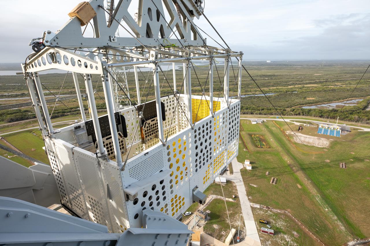 Teams with NASA’s Exploration Ground Systems Program, in preparation for the agency’s Artemis II crewed mission to the Moon, begin installing the first of four emergency egress baskets on the mobile launcher at Launch Complex 39B at the agency’s Kennedy Space Center in Florida on Wednesday, Jan. 24, 2024. The baskets, similar to gondolas on ski lifts, are used in the case of a pad abort emergency to enable astronauts and other pad personnel a way to quickly escape away from the mobile launcher to the base of the pad and where waiting emergency transport vehicles will then drive them away.