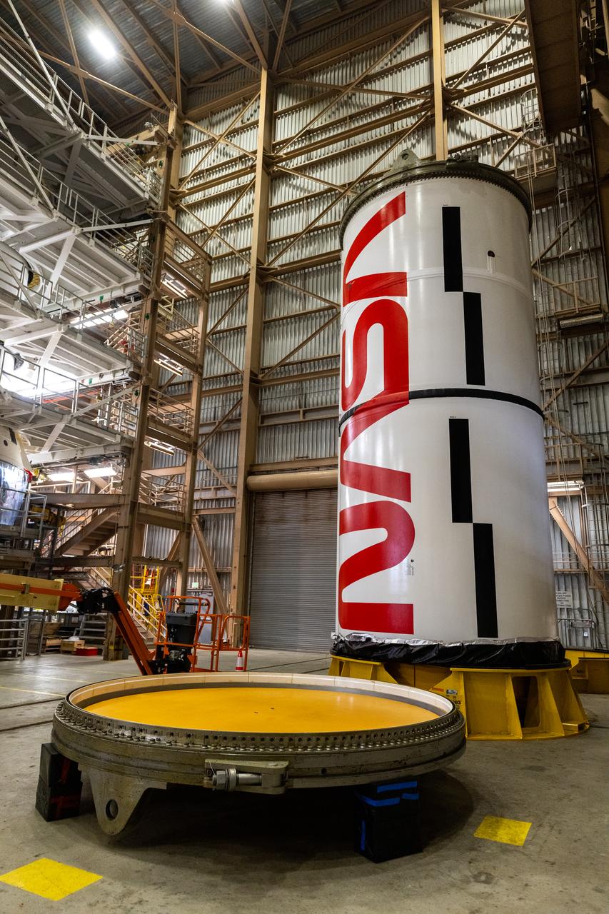 Workers with NASA’s Exploration Ground Systems and primary contractor, Jacobs, complete the painting of the agency’s iconic “worm” logo along the side of the twin Artemis II solid rocket booster motor segments inside the Rotation, Processing and Surge Facility at Kennedy Space Center in Florida on Friday, Feb. 16, 2024. Using a laser projector, the logo was mapped out with tape by workers with Jacobs, for the spaceport, before using two coats of red paint, plus several coats of clear primer to complete the logo that stretches 25 feet long. The booster segments will help propel the SLS (Space Launch System) rocket on the Artemis II mission to send four astronauts around the Moon as part of the agency’s effort to establish a long-term science and exploration presence at the Moon, and eventually Mars.