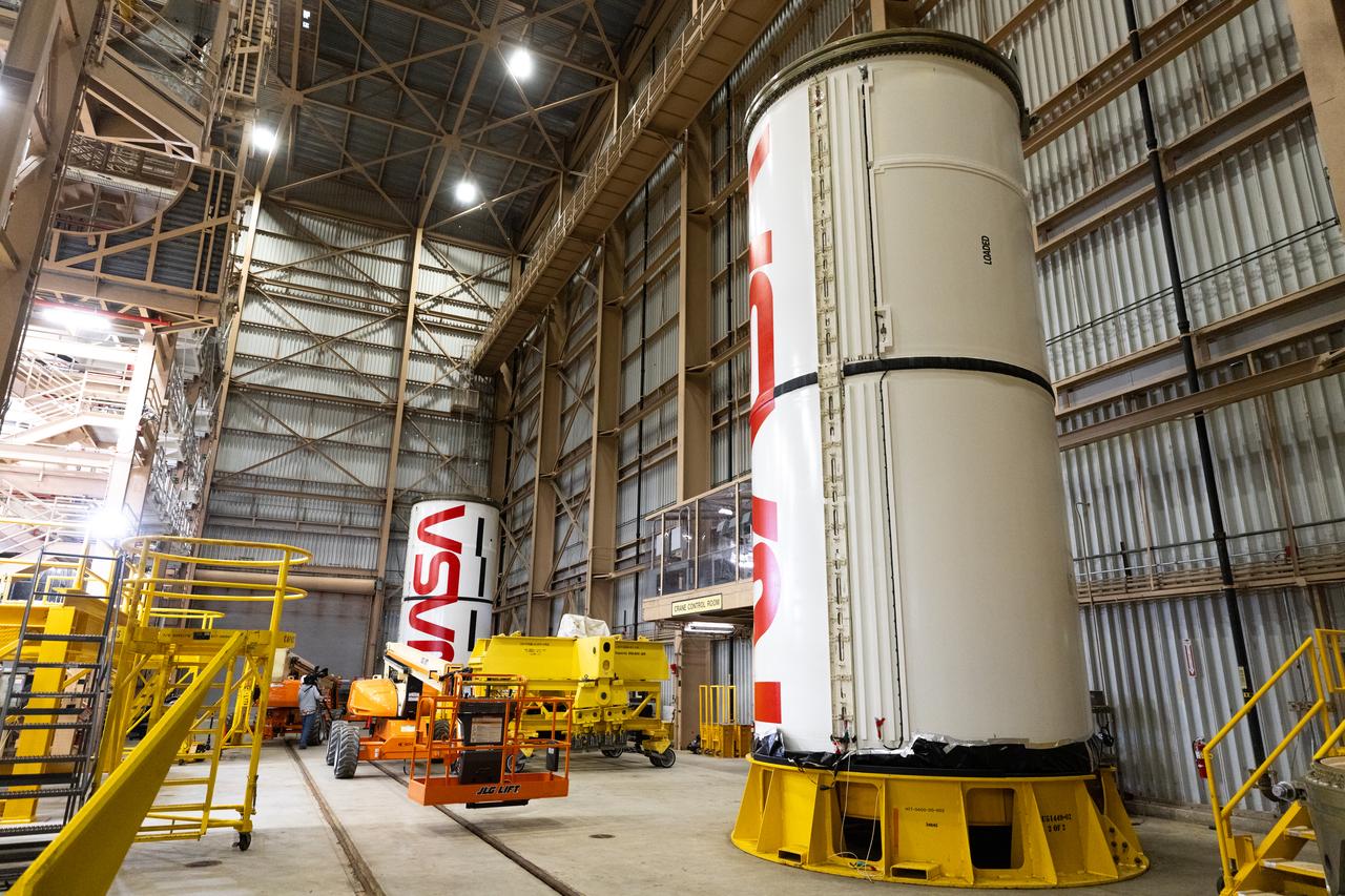 Workers with NASA’s Exploration Ground Systems and primary contractor, Jacobs, complete the painting of the agency’s iconic “worm” logo along the side of the twin Artemis II solid rocket booster motor segments inside the Rotation, Processing and Surge Facility at Kennedy Space Center in Florida on Friday, Feb. 16, 2024. Using a laser projector, the logo was mapped out with tape by workers with Jacobs, for the spaceport, before using two coats of red paint, plus several coats of clear primer to complete the logo that stretches 25 feet long. The booster segments will help propel the SLS (Space Launch System) rocket on the Artemis II mission to send four astronauts around the Moon as part of the agency’s effort to establish a long-term science and exploration presence at the Moon, and eventually Mars.