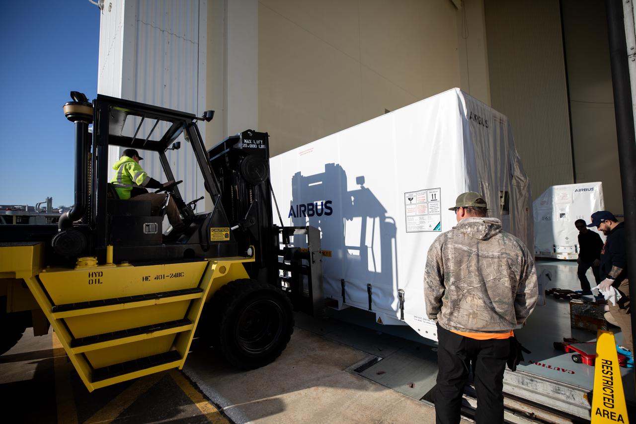 The transport carrier containing the five-panel solar arrays for NASA’s Europa Clipper spacecraft arrives at the Payload Hazardous Servicing Facility at the agency’s Kennedy Space Center in Florida on Wednesday, Feb. 21, 2024. The solar array travelled by air from Leiden, Netherlands, where Airbus workers assembled them over the last year, and then put on a barge to travel to the Port of Miami in Florida and loaded onto a semi-truck to be driven to Kennedy. The solar arrays will attach to the spacecraft to power it for the 1.8-billion-mile journey to study Jupiter’s icy moon, Europa. Launch on a SpaceX Falcon Heavy rocket is no earlier than October 2024.