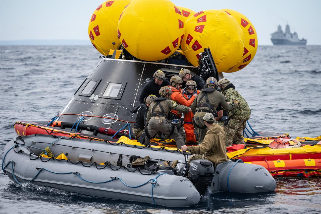 NASA Artemis II crew members are assisted by U.S. Navy personnel as they exit a mockup of the Orion spacecraft in the Pacific Ocean during Underway Recovery Test 11 (URT-11) on Feb. 25, 2024, while his crewmates look on. URT-11 is the eleventh in a series of Artemis recovery tests, and the first time NASA and its partners put their Artemis II recovery procedures to the test with the astronauts.