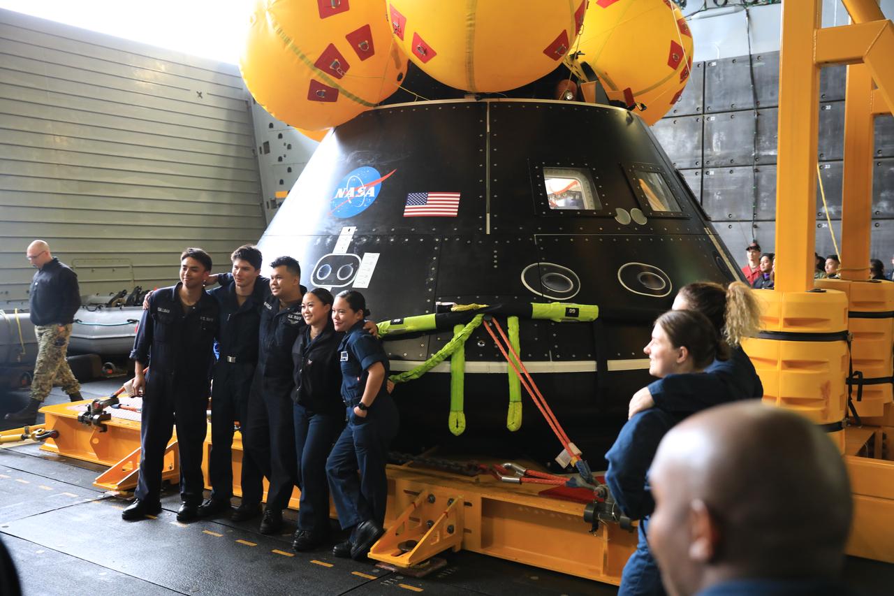 U.S. Navy personnel aboard the USS San Diego pose in front of a mockup of the Orion spacecraft during Underway Recovery Test 11 (URT-11) off the coast of San Diego, California on Monday, Feb. 26, 2024. URT-11 is the eleventh in a series of Artemis recovery tests, and the first time NASA and its partners put their Artemis II recovery procedures to the test with the astronauts. 