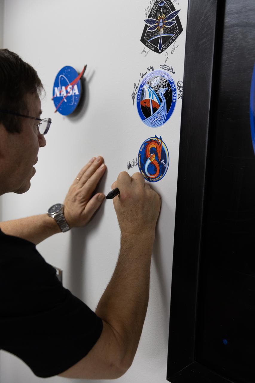 NASA astronaut Michael Barratt signs his name inside the Astronaut Crew Quarters in the Neil A. Armstrong Operations and Checkout Building at NASA’s Kennedy Space Center in Florida on Monday, February 26, 2024, ahead of NASA’s SpaceX Crew-8 mission. Crew-8 is the eighth crew rotation mission of the SpaceX Dragon spacecraft and Falcon 9 rocket that will send Barratt and NASA astronauts Matthew Dominick and Jeanette Epps, along with Roscosmos cosmonaut Alexander Grebenkin, to the International Space Station as part of the agency’s Commercial Crew Program. The mission is scheduled to launch at 12:04 a.m. EST on Friday, March 1, from Kennedy’s Launch Complex 39A. 