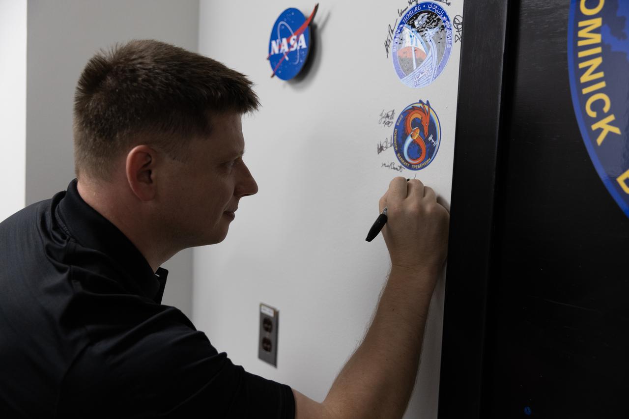 Roscosmos cosmonaut Alexander Grebenkin signs his name inside the Astronaut Crew Quarters in the Neil A. Armstrong Operations and Checkout Building at NASA’s Kennedy Space Center in Florida on Monday, February 26, 2024, ahead of NASA’s SpaceX Crew-8 mission. Crew-8 is the eighth crew rotation mission of the SpaceX Dragon spacecraft and Falcon 9 rocket that will send NASA astronauts Michael Barratt, Matthew Dominick, and Jeanette Epps, along with Grebenkin, to the International Space Station as part of the agency’s Commercial Crew Program. The mission is scheduled to launch at 12:04 a.m. EST on Friday, March 1, from Kennedy’s Launch Complex 39A. 