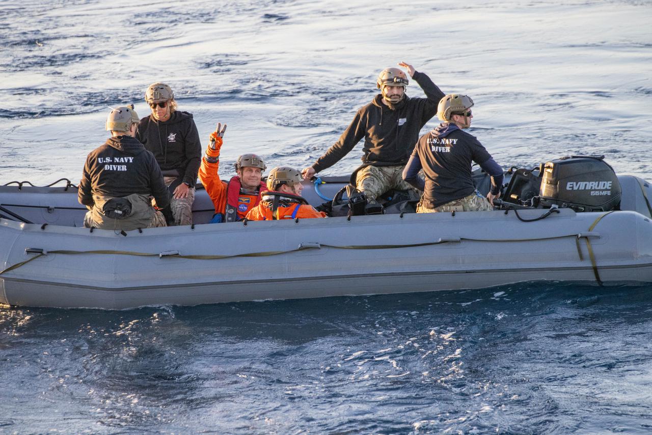 NASA’s Artemis II crew members, from back to front, NASA astronaut Reid Wiseman flashes the peace sign  with CSA (Canadian Space Agency) astronaut Jeremy Hansen while sitting in a boat during practice recovery procedures during Underway Recovery Test 11 (URT-11) off the coast of San Diego, California on Tuesday, Feb. 27, 2024. URT-11 is the eleventh in a series of Artemis recovery tests, and the first time NASA and its partners put their Artemis II recovery procedures to the test with the astronauts.