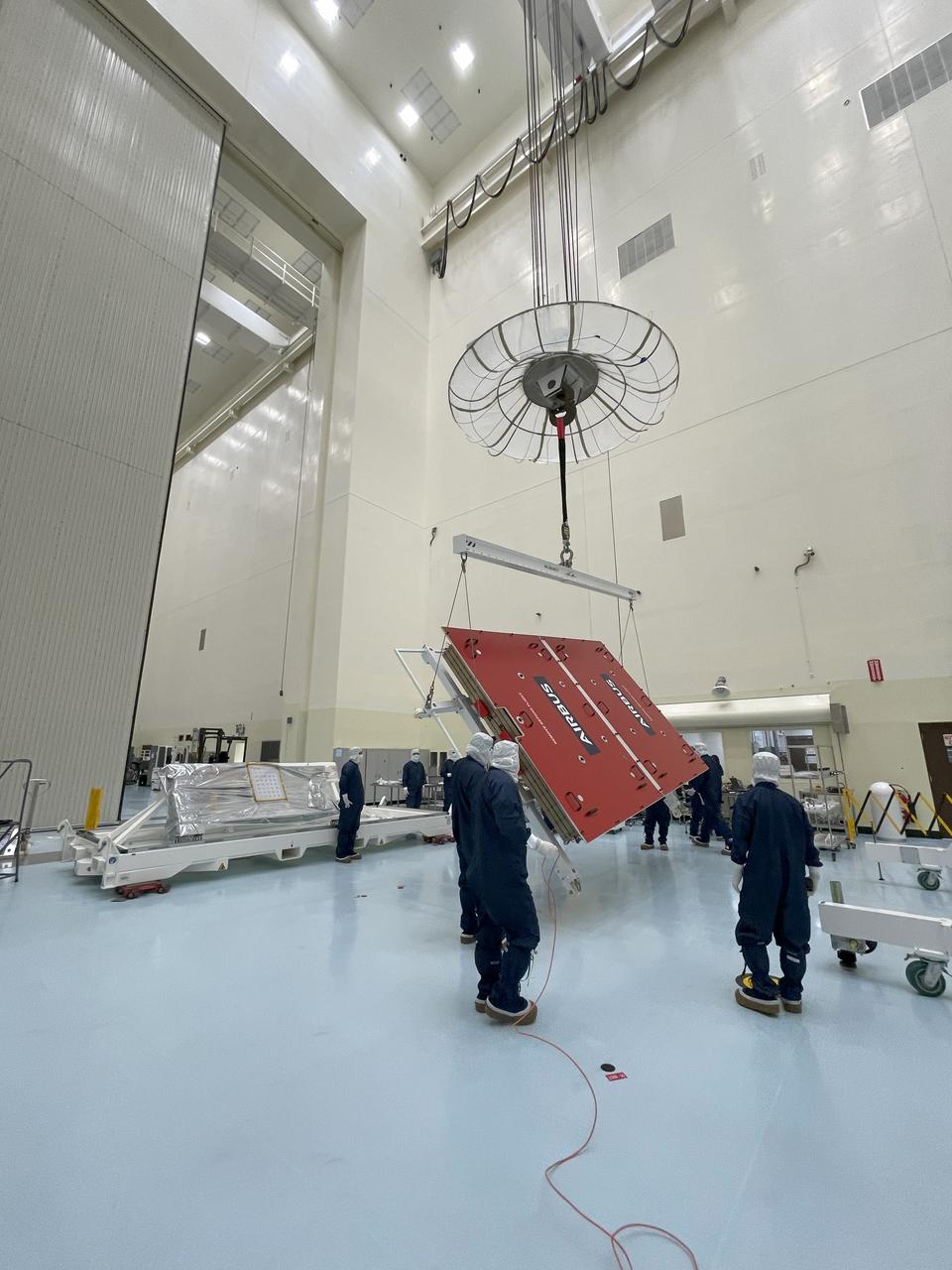 Technicians hoist a five-panel solar array protected by a lid for NASA’s Europa Clipper spacecraft at the Payload Hazardous Servicing Facility at the agency’s Kennedy Space Center in Florida on Tuesday, Feb. 27, 2024. The arrays are each 46.5 feet long (14.2 meters). With both solar arrays deployed, Europa Clipper will span more than 100 feet long, about the length of a basketball court. The solar arrays power the spacecraft so it can study Jupiter’s icy moon, Europa, which is more than five times as far from the Sun as the Earth. Launch on a SpaceX Falcon Heavy rocket is no earlier than October 2024.