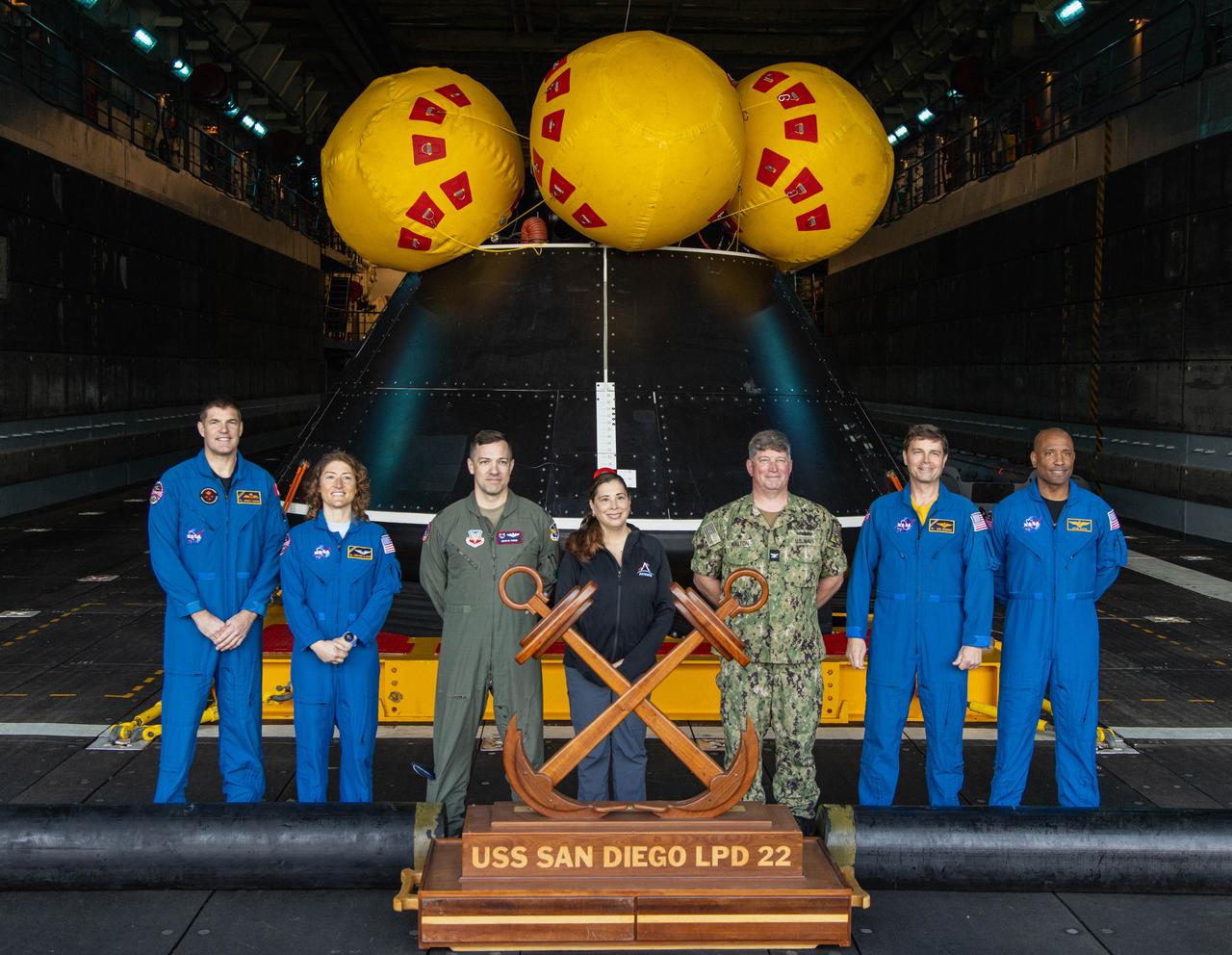 NASA’s Artemis II crew member from right to left, CSA (Canadian Space Agency) astronaut Jeremy Hansen, NASA astronaut Christina Koch, NASA’s Exploration Ground System’s Landing and Recovery team, partners from the Department of Defense, and NASA astronauts Reid Wiseman, and Victor Glover, pose for a photo near a mockup  Orion spacecraft in San Diego, California on Wednesday, Feb. 28, 2024, as part of the Underway Recovery Test (URT-11). URT-11, aboard the USS San Diego, is the eleventh in a series of Artemis recovery tests, and the first time NASA and its partners put their Artemis II recovery procedures in place involving the astronauts.
