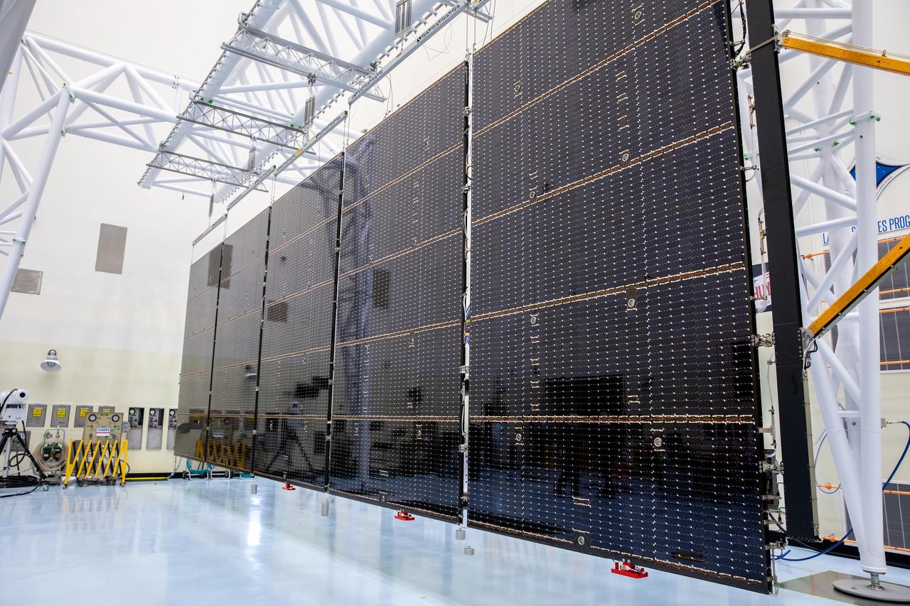 The first of two five-panel solar arrays built for NASA’s Europa Clipper is fully extended from a shipping configuration and suspended on a support system called a gravity offload fixture to begin inspection and cleaning as part of assembly, test, and launch operations inside the Payload Hazardous Servicing Facility at the agency’s Kennedy Space Center in Florida on Wednesday, March 6, 2024. Another name for the gravity offload fixture is the Transportable Large Envelope Deployment Facility (T-LEDF). When both solar arrays are installed and deployed on Europa Clipper – the agency’s largest spacecraft ever developed for a planetary mission – the spacecraft will span a total length of more than 100 feet and weigh 7,145 pounds without the inclusion of propellants.   