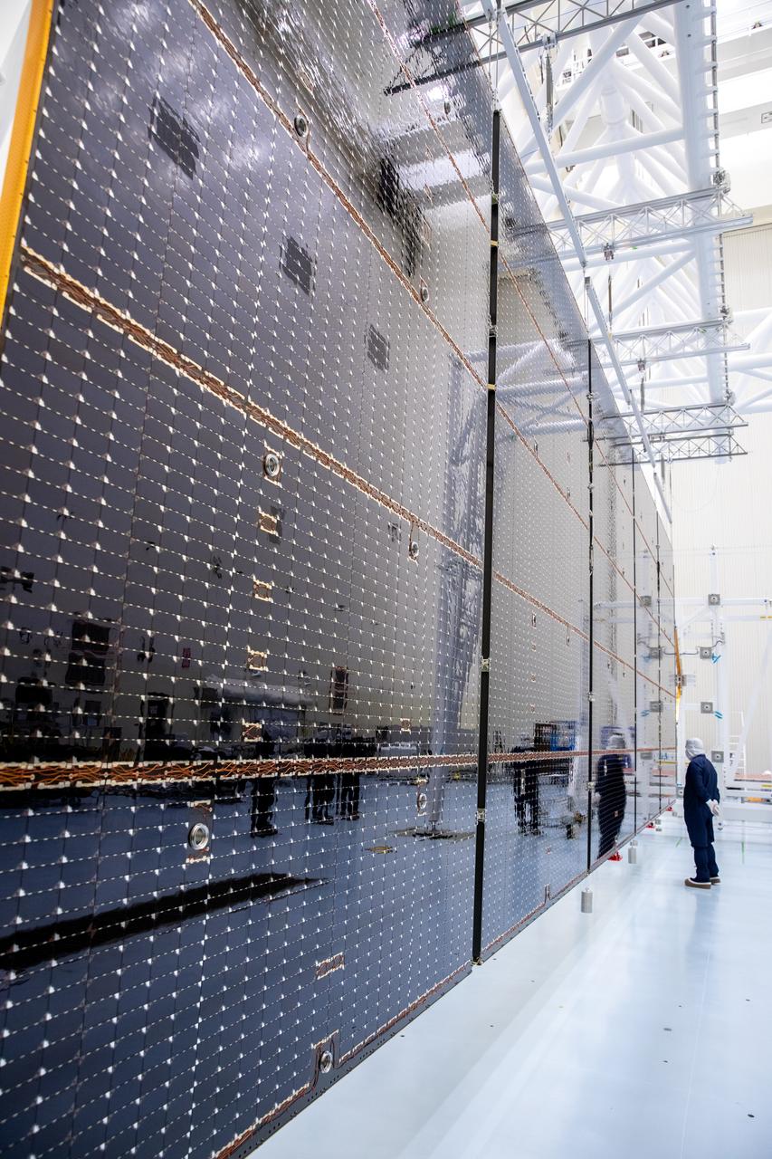 Technicians examine the first of two fully extended five-panel solar arrays built for NASA’s Europa Clipper suspended on a support system called a gravity offload fixture during inspection and cleaning as part of assembly, test, and launch operations inside the Payload Hazardous Servicing Facility at the agency’s Kennedy Space Center in Florida on Wednesday, March 6, 2024. Another name for the gravity offload fixture is the Transportable Large Envelope Deployment Facility (T-LEDF). When both solar arrays are installed and deployed on Europa Clipper – the agency’s largest spacecraft ever developed for a planetary mission – the spacecraft will span a total length of more than 100 feet and weigh 7,145 pounds without the inclusion of propellants.     