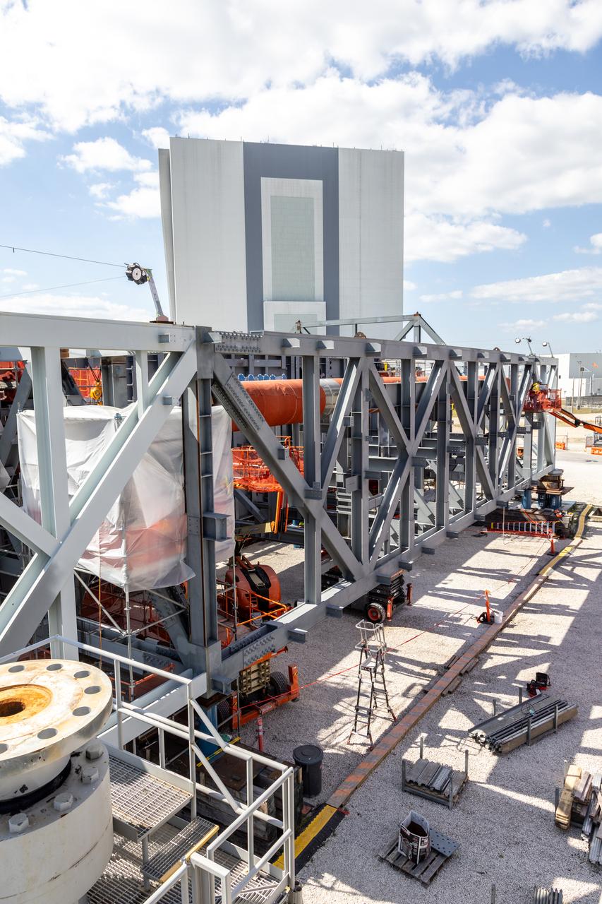 With NASA’s iconic Vehicle Assembly Building in the background, teams with the agency’s Exploration Ground Systems Program and primary contractor, Bechtel National, Inc. continue construction on the base of the platform for the new mobile launcher at Kennedy Space Center in Florida on Wednesday, April 24, 2024. Once completed and able to be carried atop the crawler-transporter, the 355-foot-tall mobile launcher 2 will be used during assembly, processing, and launch of the SLS (Space Launch System) rocket and Orion spacecraft on NASA’s upcoming Artemis missions to the Moon beginning with Artemis IV.