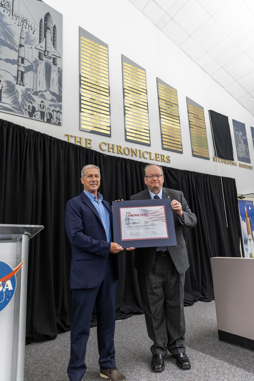Dan Billow accepts a certificate naming him a Kennedy Chronicler during a May 15 ceremony at the Press Site at NASA’s Kennedy Space Center in Florida. Presenting the award is Burt Summerfield, NASA Kennedy Space Center’s associate director, management. Billow, a retired television broadcaster, was among three reporters and industry professionals who were nominated by their peers and selected by a panel of NASA officials and current space reporters. Brass plates bearing their names were added to the wall of the “bull pen,” where reporters traditionally gather to cover launches and events at NASA Kennedy.