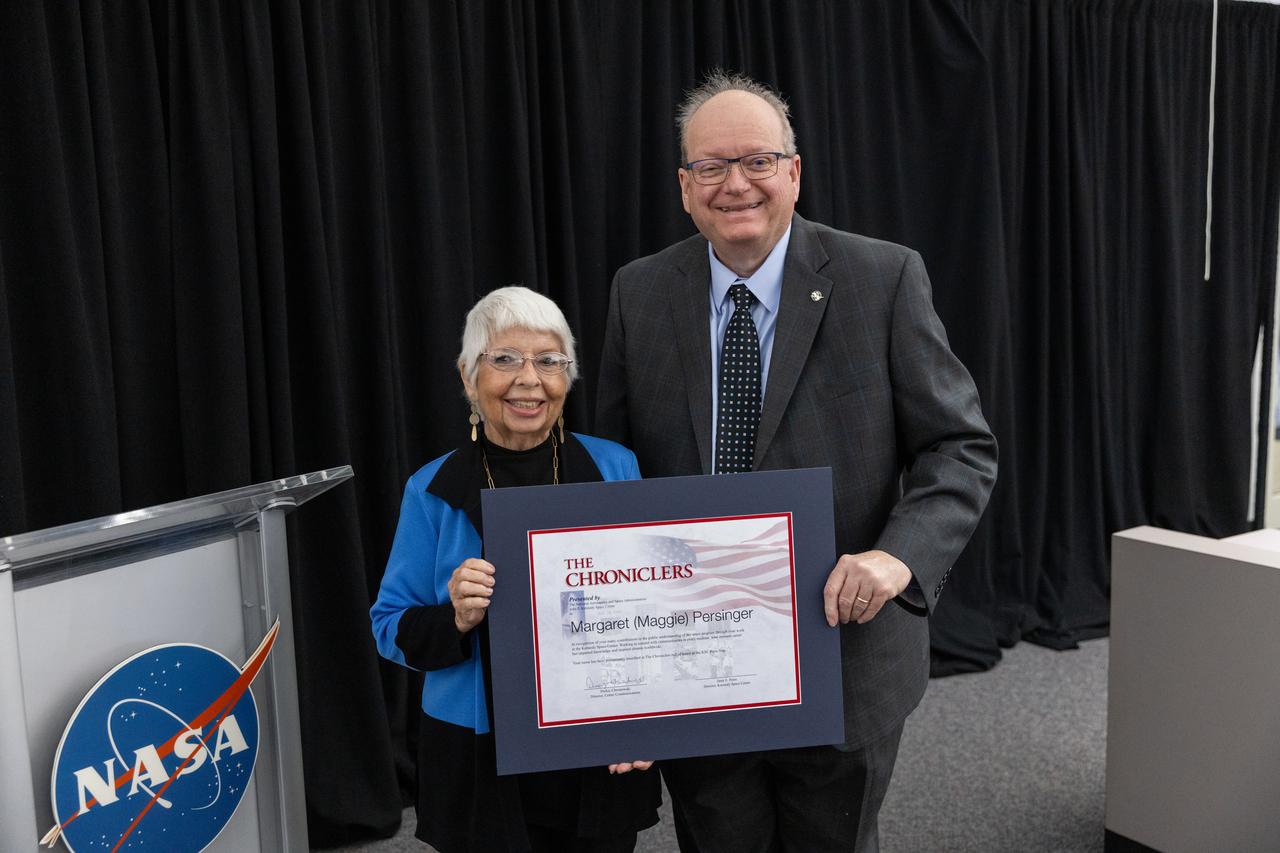 Maggie Persinger accepts a certificate naming her a Kennedy Chronicler during a May 15 ceremony at the Press Site at NASA’s Kennedy Space Center in Florida. Presenting the award is Burt Summerfield, NASA Kennedy Space Center’s associate director, management. Persinger, a retired NASA media librarian, was among three reporters and industry professionals who were nominated by their peers and selected by a panel of NASA officials and current space reporters for their efforts in helping tell the story of America’s space program. Brass plates bearing their names were added to the wall of the “bull pen,” where reporters traditionally gather to cover launches and events at NASA Kennedy.