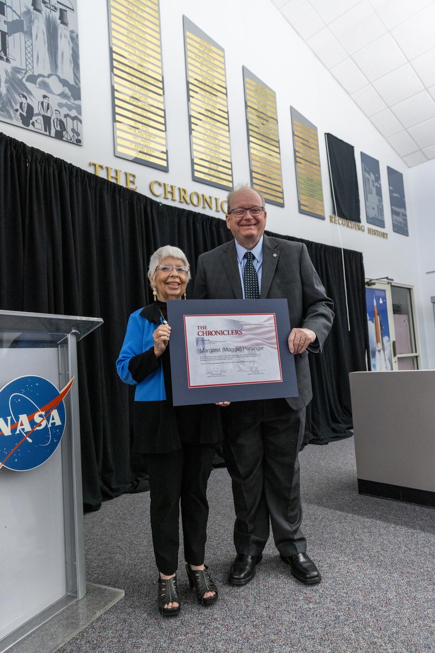 Maggie Persinger accepts a certificate naming her a Kennedy Chronicler during a May 15 ceremony at the Press Site at NASA’s Kennedy Space Center in Florida. Presenting the award is Burt Summerfield, NASA Kennedy Space Center’s associate director, management. Persinger, a retired NASA media librarian, was among three reporters and industry professionals who were nominated by their peers and selected by a panel of NASA officials and current space reporters for their efforts in helping tell the story of America’s space program. Brass plates bearing their names were added to the wall of the “bull pen,” where reporters traditionally gather to cover launches and events at NASA Kennedy.