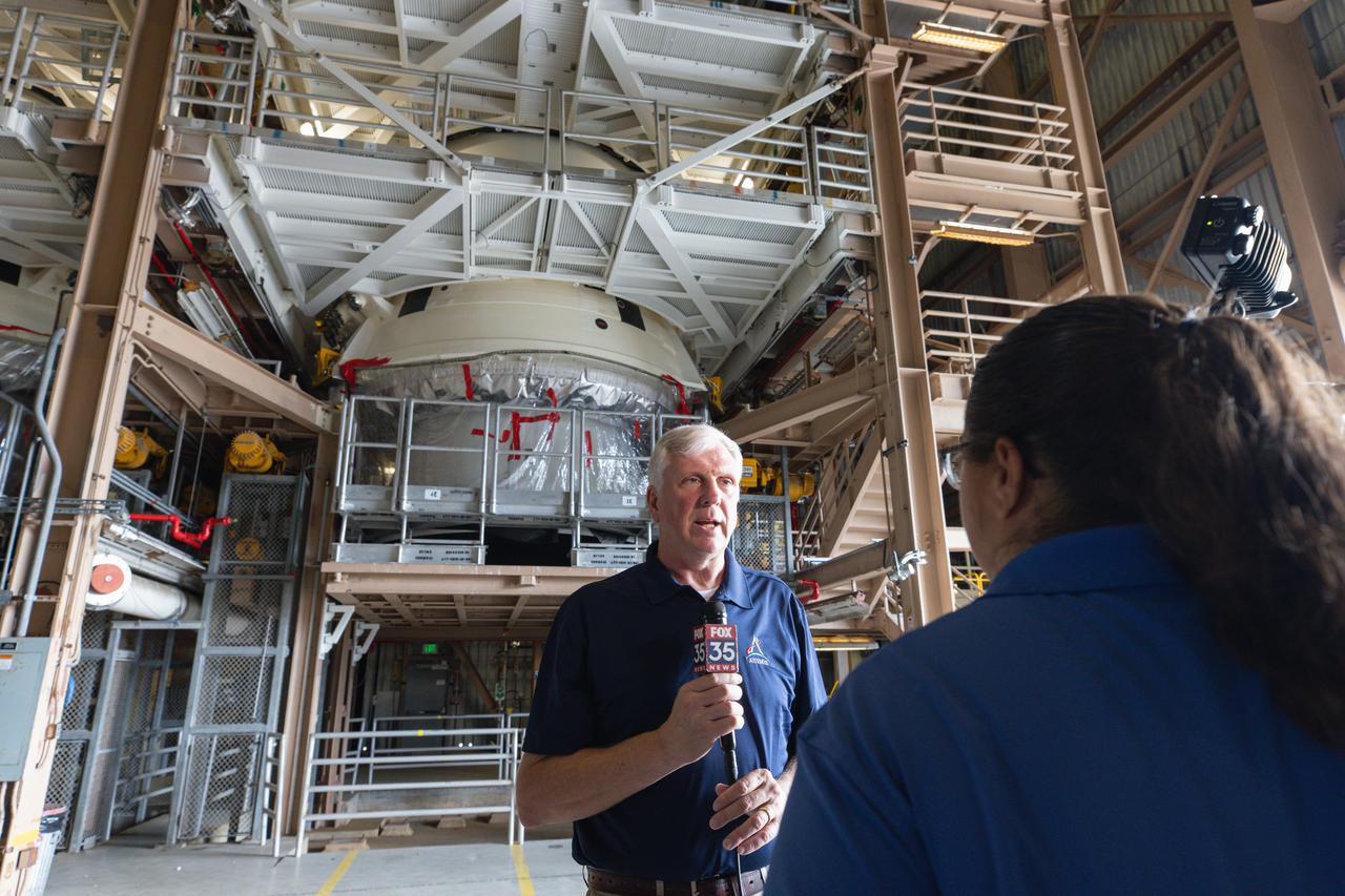 A member of the media reports near one of the aft skirts of the solid rocket booster segments inside the Rotation, Processing and Surge Facility (RPSF) at Kennedy Space Center in Florida on Tuesday, July 23, 2024. The booster segments will help propel the SLS (Space Launch System) rocket on the Artemis II mission to send four astronauts around the Moon as part of the agency’s effort to establish a long-term science and exploration presence at the Moon, and eventually Mars.