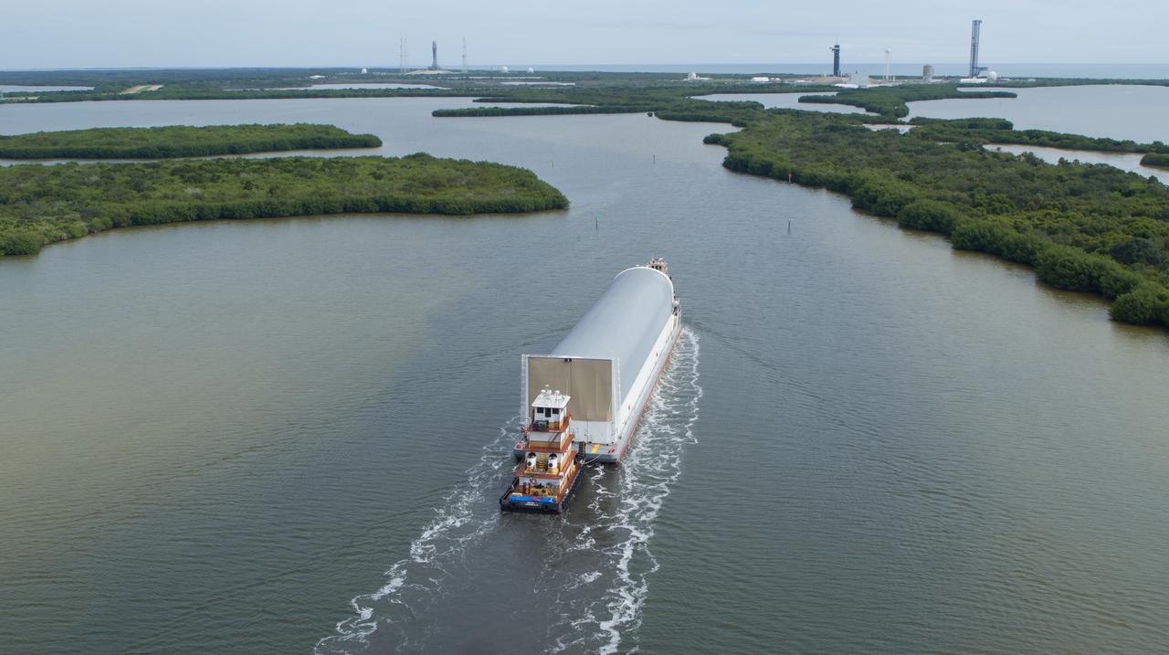 In this aerial view, NASA’s Pegasus barge, carrying the agency’s massive SLS (Space Launch System) core stage, arrives at NASA’s Kennedy Space Center Complex 39 turn basin wharf in Florida on Tuesday, July 23, 2024, after journeying from the agency’s Michoud Assembly Facility in New Orleans. The core stage is the next piece of Artemis hardware to arrive at the spaceport and will be offloaded and moved to NASA Kennedy’s Vehicle Assembly Building, where it will be prepared for integration ahead of the Artemis II launch.