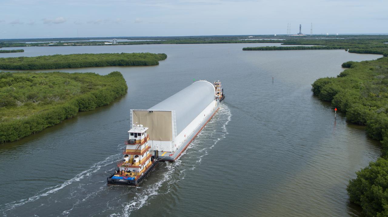 In this aerial view, NASA’s Pegasus barge, carrying the agency’s massive SLS (Space Launch System) core stage, arrives at NASA’s Kennedy Space Center Complex 39 turn basin wharf in Florida on Tuesday, July 23, 2024, after journeying from the agency’s Michoud Assembly Facility in New Orleans. The core stage is the next piece of Artemis hardware to arrive at the spaceport and will be offloaded and moved to NASA Kennedy’s Vehicle Assembly Building, where it will be prepared for integration ahead of the Artemis II launch.
