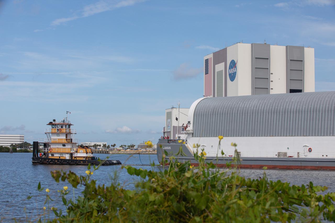 NASA’s Pegasus barge, carrying the agency’s massive SLS (Space Launch System) core stage, arrives at NASA’s Kennedy Space Center Complex 39 turn basin wharf in Florida on Tuesday, July 23, 2024, after journeying from the agency’s Michoud Assembly Facility in New Orleans. The core stage is the next piece of Artemis hardware to arrive at the spaceport and will be offloaded and moved to NASA Kennedy’s Vehicle Assembly Building, where it will be prepared for integration ahead of the Artemis II launch.