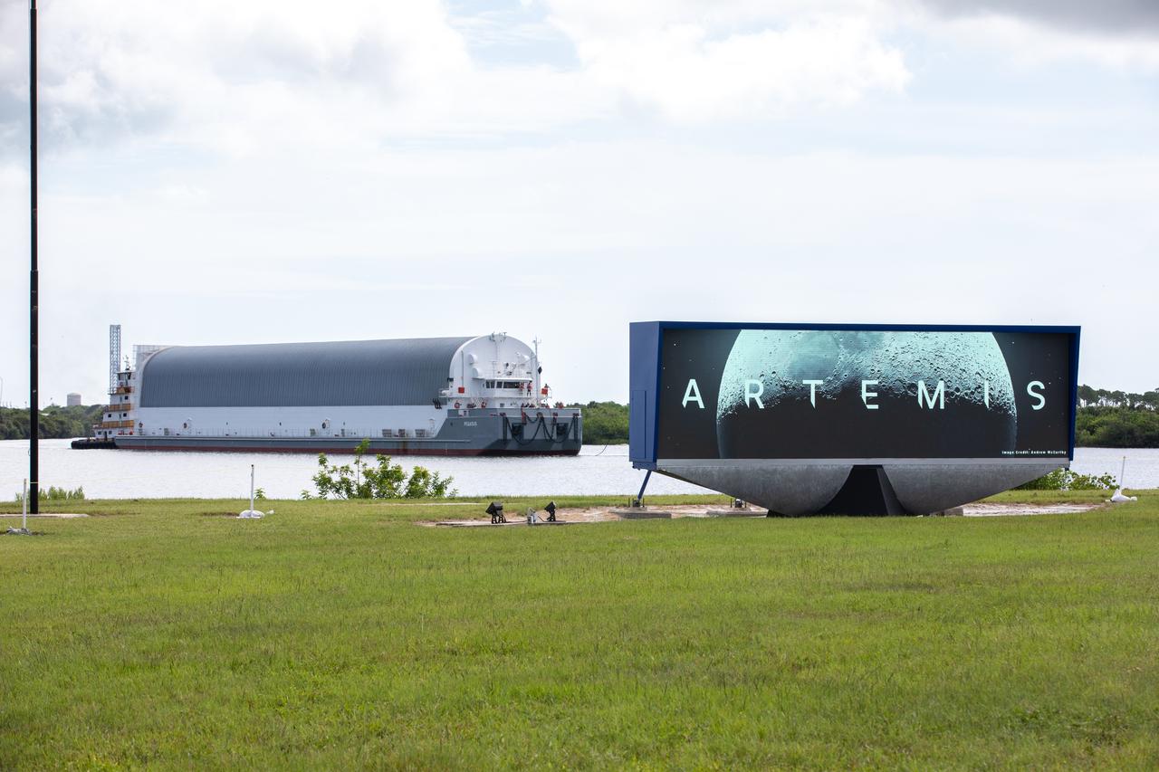 Behind the iconic countdown clock at NASA’s Kennedy Space Center in Florida, the agency’s Pegasus barge completes its 900-mile journey from NASA’s Michoud Assembly Facility in New Orleans carrying the powerful SLS (Space Launch System) core stage on Tuesday, July 23, 2024. Teams with Exploration Ground Systems (EGS) will offload the rocket stage and transfer it to the spaceport’s Vehicle Assembly Building to prepare it for integration atop the mobile launcher ahead of the Artemis II launch.