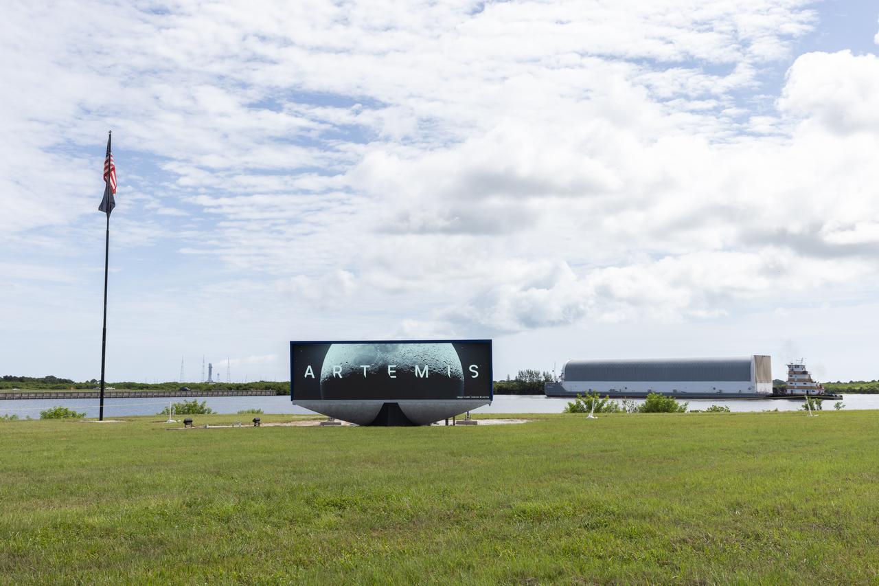 Behind the iconic countdown clock at NASA’s Kennedy Space Center in Florida, the agency’s Pegasus barge completes its 900-mile journey from NASA’s Michoud Assembly Facility in New Orleans carrying the powerful SLS (Space Launch System) core stage on Tuesday, July 23, 2024. Teams with Exploration Ground Systems (EGS) will offload the rocket stage and transfer it to the spaceport’s Vehicle Assembly Building to prepare it for integration atop the mobile launcher ahead of the Artemis II launch.
