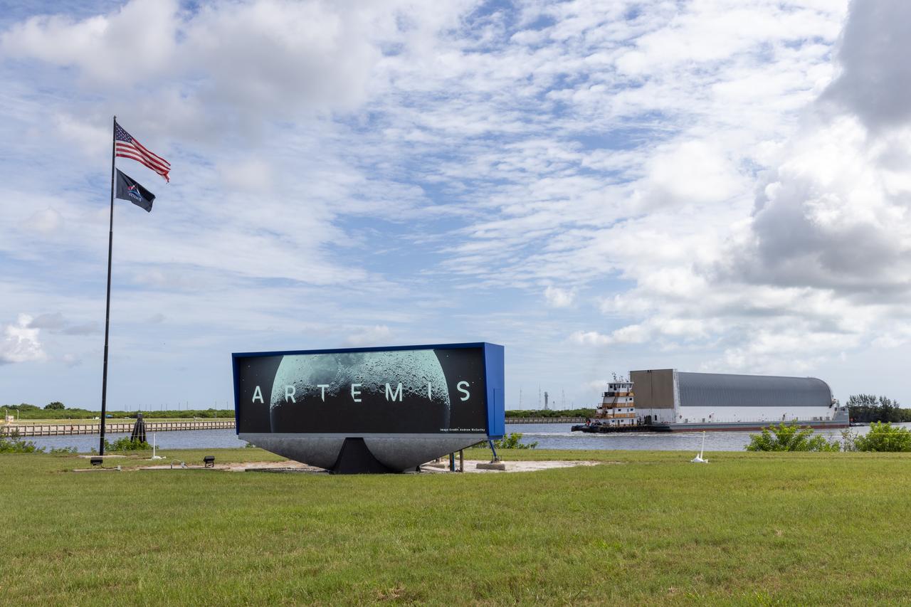 Behind the iconic countdown clock at NASA’s Kennedy Space Center in Florida, the agency’s Pegasus barge completes its 900-mile journey from NASA’s Michoud Assembly Facility in New Orleans carrying the powerful SLS (Space Launch System) core stage on Tuesday, July 23, 2024. Teams with Exploration Ground Systems (EGS) will offload the rocket stage and transfer it to the spaceport’s Vehicle Assembly Building to prepare it for integration atop the mobile launcher ahead of the Artemis II launch.