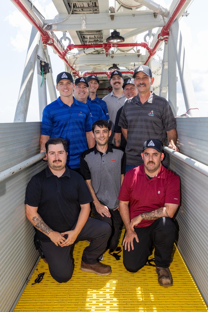 Some of the team members who make up the Artemis closeout team pose for a picture at Launch Complex 39B at NASA’s Kennedy Space Center in Florida on Tuesday, Aug. 13, 2024. Members of the closeout crew, pad rescue team, and the Exploration Ground Systems Program practiced the process of getting inside and out of the emergency egress baskets. While the crew and other personnel will ride the emergency egress baskets to the terminus area in a real emergency, no one rode the baskets for this test. Instead, teams tested the baskets during separate occasions by using water tanks filled to different levels to replicate simulate the weight of passengers.