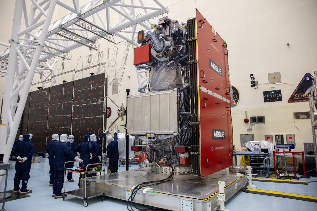 Technicians install and align the second set of solar arrays for NASA’s Europa Clipper spacecraft inside the agency’s Payload Hazardous Servicing Facility at Kennedy Space Center in Florida on Thursday, Aug. 15, 2024. The Europa Clipper spacecraft will need the 46.5 feet (14.2 meter) long, five-panel solar arrays on each side, to gather enough sunlight to power the spacecraft to perform flybys around Jupiter’s icy moon, Europa, so science instruments aboard the spacecraft can determine if the moon could hold the building blocks necessary to sustain life. 