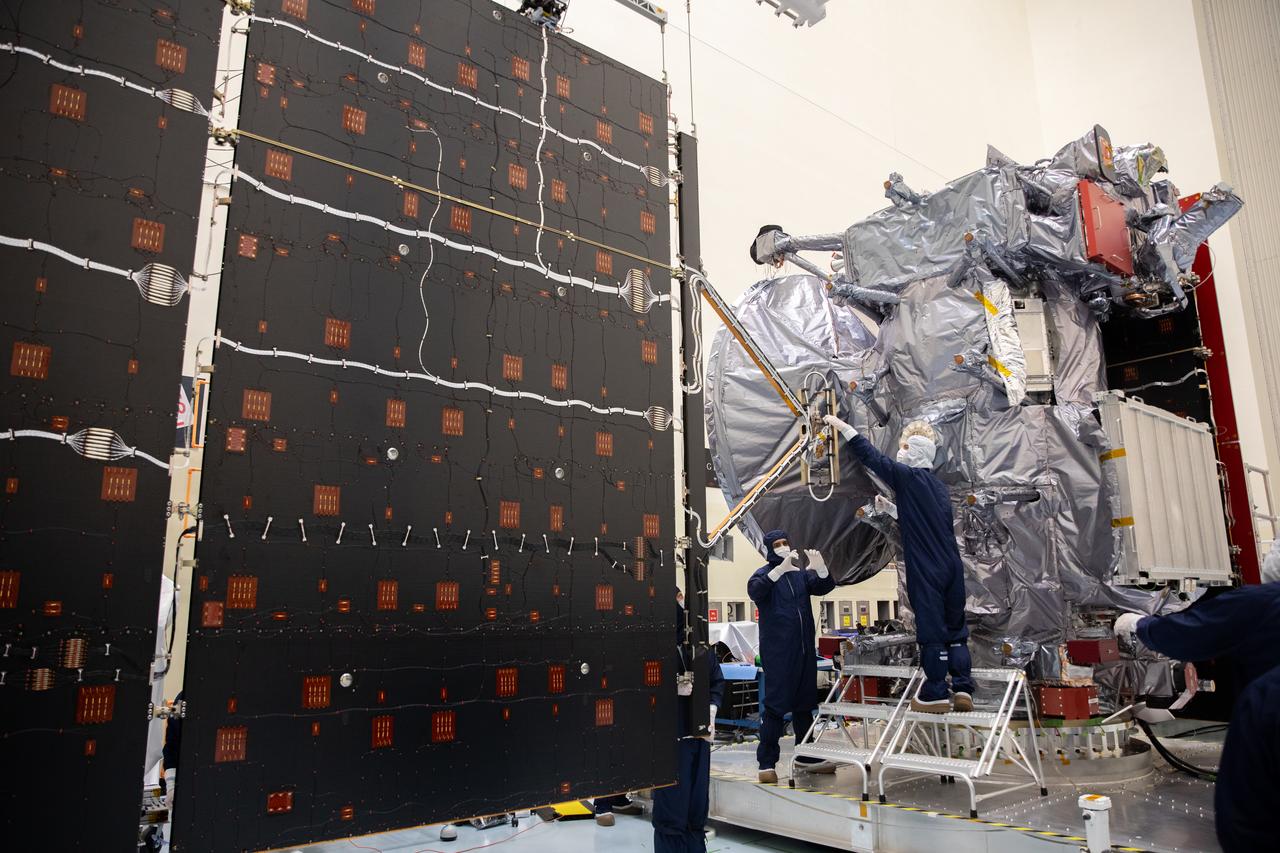 Technicians install and align the second set of solar arrays for NASA’s Europa Clipper spacecraft inside the agency’s Payload Hazardous Servicing Facility at Kennedy Space Center in Florida on Thursday, Aug. 15, 2024. The Europa Clipper spacecraft will need the 46.5 feet (14.2 meter) long, five-panel solar arrays on each side, to gather enough sunlight to power the spacecraft to perform flybys around Jupiter’s icy moon, Europa, so science instruments aboard the spacecraft can determine if the moon could hold the building blocks necessary to sustain life. 