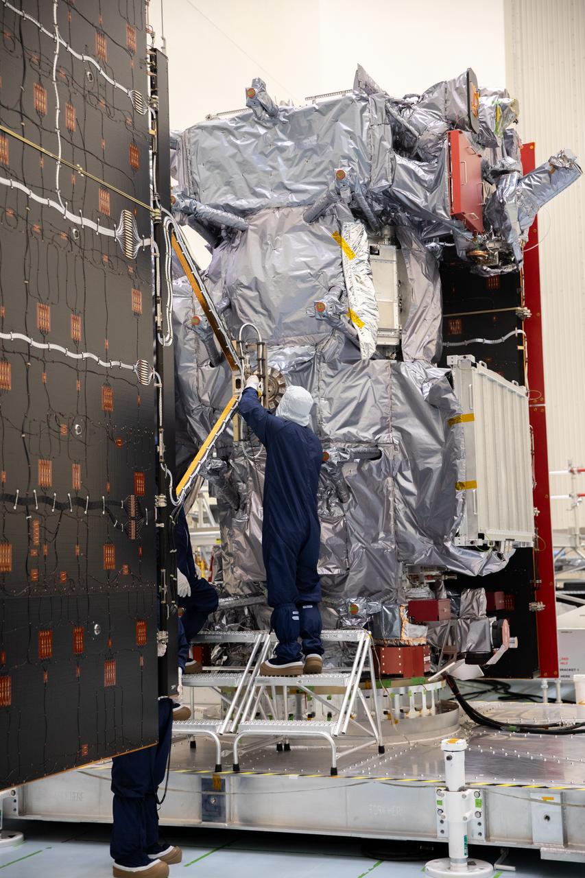Technicians install and align the second set of solar arrays for NASA’s Europa Clipper spacecraft inside the agency’s Payload Hazardous Servicing Facility at Kennedy Space Center in Florida on Thursday, Aug. 15, 2024. The Europa Clipper spacecraft will need the 46.5 feet (14.2 meter) long, five-panel solar arrays on each side, to gather enough sunlight to power the spacecraft to perform flybys around Jupiter’s icy moon, Europa, so science instruments aboard the spacecraft can determine if the moon could hold the building blocks necessary to sustain life. 