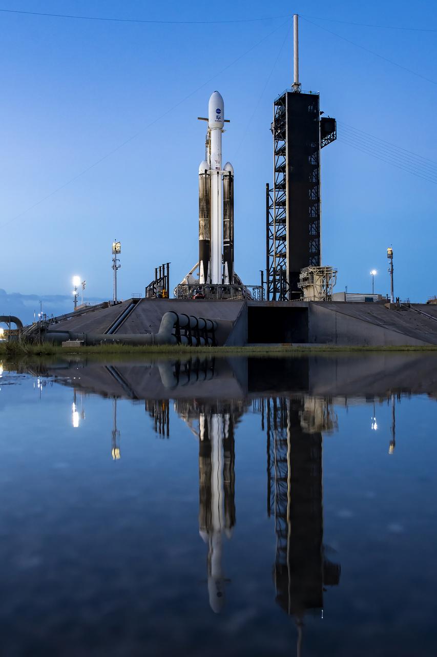 A reflection in the water shows NASA’s Europa Clipper spacecraft atop SpaceX’s Falcon Heavy rocket at Launch Pad 39A on Sunday, Oct. 13, 2024, at the agency’s Kennedy Space Center in Florida ahead of launch to Jupiter’s icy moon, Europa. The spacecraft will complete nearly 50 flybys of Europa to determine if there are conditions suitable for life beyond Earth. Launch is targeting 12:06 p.m. EDT on Monday, Oct. 14, from Launch Complex 39A at Kennedy Space Center in Florida.